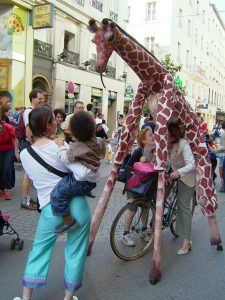 Două girafe și puiul lor se plimbă pe străzile orașului pe un fond sonor care recreează auditiv sunetele savanei
